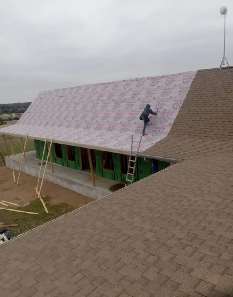 Worker preparing underlayment for a metal roof installation in Lacy-Lakeview